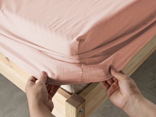 Light pink fitted bottom sheet, providing a snug and stylish fit for your bed.
