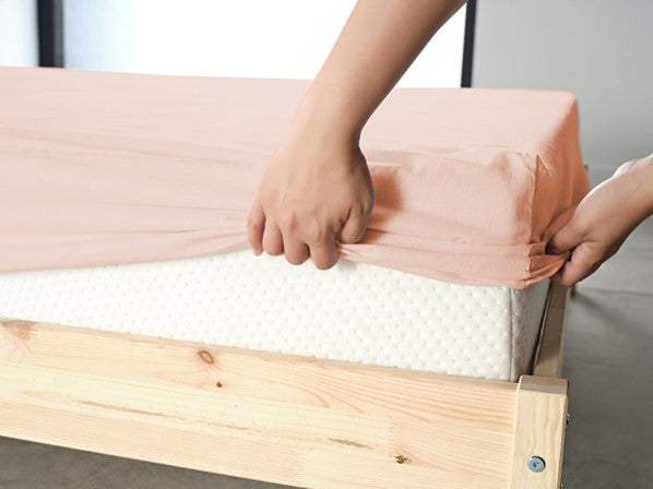Light pink fitted bottom sheet, providing a snug and stylish fit for your bed.